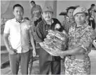  ??  ?? EWON menyerahka­n POD kepada salah seorang Ketua Platun Rela Left (R) Minor Selom dari Mukim Karagasan, sambil diiringi Agku Damit (kiri) dan Japirin.