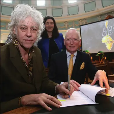  ??  ?? Sir Bob Geldof signs a contract at the National Library of Ireland (NLI) in Dublin with Chairman Paul Shovlin and library director Dr Sandra Collins, as he announced that the Band Aid Trust is donating its archive to the NLI