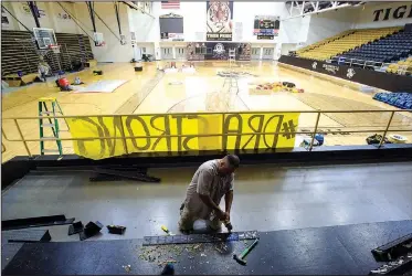  ?? NWA Democrat-Gazette/CHARLIE KAIJO ?? Jose Portillo, a contractor from NWA Restore It, removes old glue from base moldings Monday at Bentonvill­e High School’s gymnasium. The moldings had to be removed to dry water underneath the basketball court after rain from a storm about two weeks ago leaked through the roof of the gym causing 3 to 4 inches of water to flood the floor, said Peter Hader from NWA Restore It.