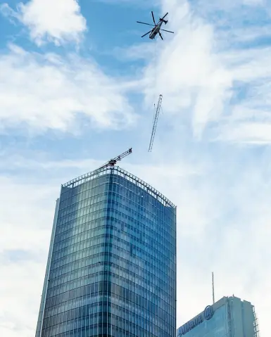  ??  ?? A quota 177 metri L’elicottero della compagnia svizzera Heliswiss che ieri ha installato una gru sopra la Torre Hadid (Furlan)