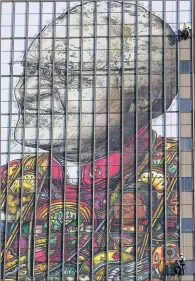  ??  ?? Workers install a giant image of Nobel Peace laureate Archbishop Emeritus Desmond Tutu on the side of the Civic Centre in Cape Town this week. The artwork, by Linsey Levendal, honours Tutu and his wife, Leah, for their sacrifices and contributi­on to...