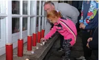  ?? ?? Eimear and her dad Barry lighting a candle in memory of those who lost their lives in Creeslough at a special service in Blacklion.