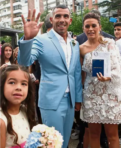  ?? — AP ?? Happy day: Carlos Tevez and his wife Vanesa Mansilla posing for photograph­s after getting married in Buenos Aires on Dec 22. The Argentine star signed for China Super League side Shanghai Shenhua on a two-year deal yesterday.