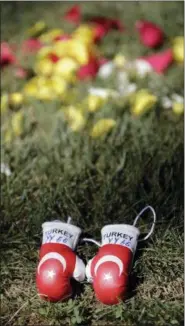  ?? MARK HUMPHREY — THE ASSOCIATED PRESS ?? Miniature boxing gloves left by Yusuf Anac, a Turk now living in Bochum, Germany, lie on the grave of boxing great Muhammad Ali, Saturday in Louisville, Ky. Cave Hill Cemetery opened to the public Saturday, the day after Ali’s burial.