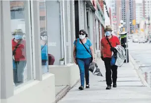 ?? SEAN KILPATRICK THE CANADIAN PRESS ?? A couple wear masks while out for a walk in Ottawa on Friday. Most Ontario businesses were ordered to close in March, but some will be allowed to reopen on Monday.