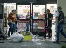  ?? Gina Ferazzi Los Angeles Times ?? WORKERS at Smart & Final clean up debris caused by looting. Graffiti in English, Spanish and Spanglish marked buildings, walls, curbs and trees in Santa Ana.