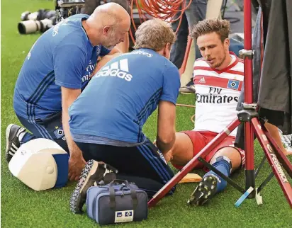  ?? FOTO: DPA ?? Sorgenvoll­e Mienen: Betreuer vom Hamburgers SV umsorgen Nicolai Müller nach seinem verunglück­ten Torjubel.