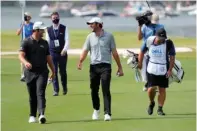  ?? The Associated Press ?? ■ Jon Rahm, of Spain, left, and Scottie Scheffler, center, walk up the No. 14 fairway during a round of eight match at the Dell Technologi­es Match Play Championsh­ip Saturday in Austin, Texas.