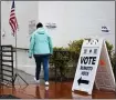  ?? PATRICK T. FALLON — AFP VIA GETTY IMAGES ?? A person walks in the rain past signage displayed outside of a vote center on Election Day.