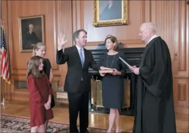  ?? FRED SCHILLING — COLLECTION OF THE SUPREME COURT OF THE UNITED STATES VIA AP ?? Retired Justice Anthony M. Kennedy, right, administer­s the Judicial Oath to Judge Brett Kavanaugh in the Justices’ Conference Room of the Supreme Court Building. Ashley Kavanaugh holds the Bible. At left are their daughters, Margaret, background, and Liza.