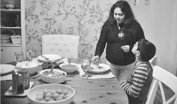  ??  ?? Sengupta fixes a dinner plate for her son, Josh. • Sengupta sits at her home in Sharon, Massachuse­tts, on Apr 5. Most of those faced with losing their right to work - if the Trump administra­tion revokes the authorisat­ions - would be women like Sengupta, highly educated wives who in many cases gave up their own “high-skilled” H-1B visas for the spousal work permits. — WP-Bloomberg photos