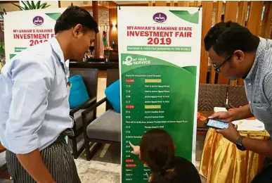  ?? — Reuters ?? New ventures: Investors looking at the schedule of the Rakhine State Investment Fair at Ngapali beach in Thandwe, Myanmar.