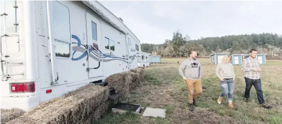  ??  ?? Woodwynn Farms’ volunteer Nicholas Fodor, left, walks past a trailer with residents Kylie Janzen and Ryan Colwell.