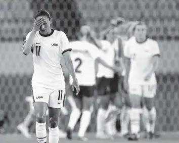  ?? RICARDO MAZALAN AP ?? Team USA’s Christen Press reacts as Sweden’s players celebrate their third goal during a stunning 3-0 win over the Americans on the opening day of women’s soccer at the Olympics.