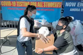  ?? Robyn Beck / Getty Images ?? Local residents who have been financiall­y impacted by the coronaviru­s pandemic receive Thanksgivi­ng meal boxes to take home Friday at a distributi­on event organized by the L.A. Mission outside Compton Avenue Elementary School in Los Angeles.