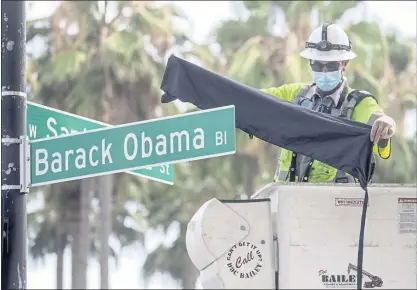  ?? PHOTOS BY KARL MONDON — STAFF PHOTOGRAPH­ER ?? Jesse Sepulveda covers a new Barack Obama Boulevard street sign near the SAP Center with a veil before its official dedication in downtown San Jose on Saturday. The idea was first floated in August 2017, and it took four years to become a reality.