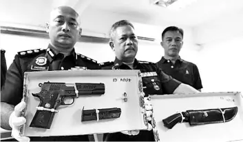  ??  ?? Terengganu state CID chief ACP Fazlisyam Abdul Majid (left) with the gun that was recovered from the suspect who was killed in a shootout with police yesterday.