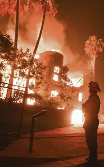  ?? Pictures: AP ?? A firefighte­r keeps watch as the Woolsey fire burns a home in Malibu, California. BELOW LEFT: Krystin Harvey, left, comforts her daughter Araya Cipollini at the remains of their home burned at Paradise. BELOW RIGHT: The charred remains of a home in Malibu.