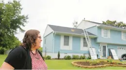  ?? JONATHON GRUENKE/STAFF ?? Hampton resident Katrina Dash watches as a crew installs solar panels on the roof of her home last week.“Making our own clean energy and trying to reduce our footprint as much as possible” is important, Dash said.