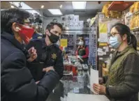  ?? STEPHEN LAM / GETTY IMAGES ?? A storekeepe­r speaks with a police chief and Carl Chan, president of Oakland’s Chinatown Chamber of Commerce, in California on Feb 16. The community is on heightened alert after recent increases in violent crimes against Asian Americans.