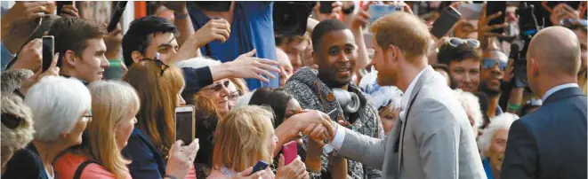  ?? ODD ANDERSEN AGENCE FRANCE-PRESSE ?? Le prince de Galles (au veston gris), Harry, a pris le temps de rencontrer des admirateur­s, à la veille de son mariage avec Meghan Markle, vendredi, à Windsor.