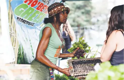  ??  ?? Beverly Grant arranges her farmers market stand at The Garden in the Park Hill. This was the first Mo’ Betta Green farmers market at The Garden. Grant started the farmers market in 2011. Brent Lewis, The Denver Post