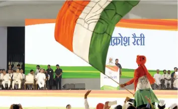  ?? — PRITAM BANDYOPADH­YAY ?? A Congress supporter waves tricolour, while former Prime Minister Manmohan Singh addresses the Jan Aakrosh rally in New Delhi on Sunday.