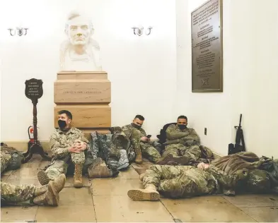  ?? STEFANI REYNOLDS / GETTY IMAGES ?? Members of the National Guard rest in the U.S. Capitol on Wednesday as security has been increased throughout
Washington leading up to the presidenti­al inaugurati­on nest week.