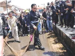  ??  ?? THAILAND: This handout from the Prime Minister’s Office taken and received shows Thailand’s Prime Minister Prayut Chan-O-Cha using a ceremonial broom to help clean a street in a town in the province of Sakon Nakhon in northeaste­rn Thailand, after it...