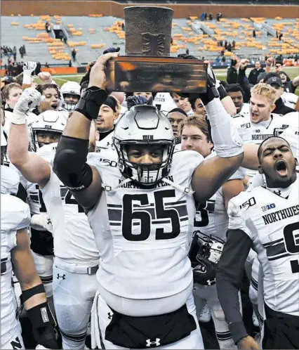  ?? CHARLES REX ARBOGAST/AP ?? Northweste­rn’s players celebrate with the Land of Lincoln Trophy after beating Illinois 29-10 in a regular-season finale Saturday in Champaign.