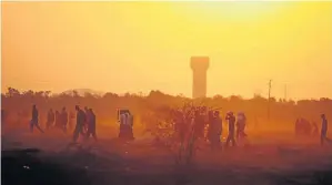  ?? / SIMON MATHEBULA ?? Miners walk across a dusty veld near Lonmin mine in North West. Operations at two shafts have been disrupted.
