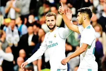  ?? — AFP photo ?? Real Madrid’s Spanish midfielder Marco Asensio (R) celebrates with Real Madrid’s Spanish defender Nacho Fernandez after scoring a goal during the Spanish league football match Real Madrid CF vs SD Eibar at the Santiago Bernabeu stadium in Madrid on...