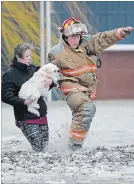 ?? BARRY GRAY THE HAMILTON SPECTATOR ?? A Hamilton firefighte­r steps carefully through high water as he helps Maggie Thibodeau, carrying dog Carrie, to safety after several homes were flooded on Church Street at Green Road in Stoney Creek on Sunday. Thibodeau says she called the city...