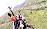  ??  ?? PENGALAMAN salah seorang peserta tandem paraglidin­g bersama Juruterban­g Jestini Salim (belakang).