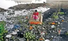  ?? THE ASSOCIATED PRESS ?? Ram Nath, 40, who makes a living from recycling trash, rummages for plastic bottles and other reusable trash while rowing a boat through waters of Yamuna, India’s sacred river that flows through the capital of New Delhi.