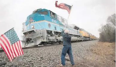  ?? SCOTT OLSON/GETTY ?? Peter Olyniec waves a flag as a train carrying the remains of former President George H.W. Bush to his final resting place in Texas passes by.