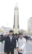  ?? — AFP ?? People gather next to a replica of a Sejil medium-range missile during a demonstrat­ion outside the former US Embassy in Tehran on Saturday.