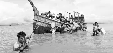  ??  ?? Rohingya refugees get off a boat after crossing the Bangladesh-Myanmar border through the Bay of Bengal in Shah Porir Dwip, Bangladesh. — Reuters photo