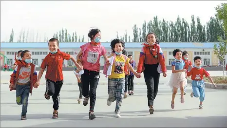  ?? GAO HAN / XINHUA ?? Children in a village of Pishan county, Xinjiang, leave school after class in June.