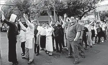  ?? DIANA ULLOA/GETTY-AFP ?? Hotel workers raise their arms to show they are OK after a seismic alarm sounded Saturday in Mexico City.