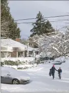  ?? The Associated Press ?? People make their way through a snowcovere­d street in the Grand Park neighbourh­ood of Portland, Ore., Thursday.