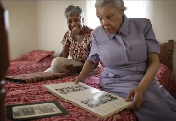  ?? PHOTOS BY LINDA DAVIDSON, WASHINGTON POST ?? Loretta Veney, 57, left, looks at scrap books and yearbooks with her mother Doris Woodward, 86, who has dementia. Veney wrote a book about her experience as a caregiver.