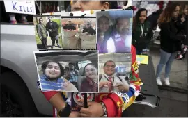  ?? JANE TYSKA — STAFF PHOTOGRAPH­ER ?? A woman holds a sign with pictures during a vigil for crash victim Lolomanaia “Lolo” Soakai on Internatio­nal Boulevard near 54th Avenue in Oakland on Wednesday. A group calling itself the Traffic Violence Rapid Response Team led the vigil for Soakai, 28, who died Sunday.