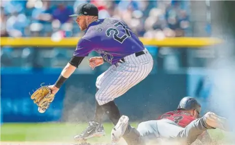  ?? Dustin Bradford, Getty Images ?? Rockies shortstop Trevor Story, attempting to control a throw in a game this season while Christian Walker of the Diamondbac­ks steals second base, takes on Arizona in a three-game series starting Tuesday night at Coors Field.