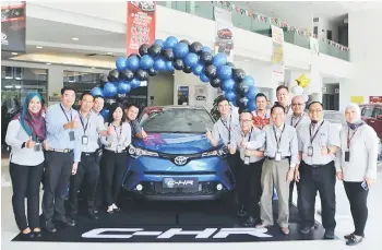  ??  ?? Senior sales manager Hussen Ali Hassan (front, third right) and his staff pose with the 2018 Toyota C-HR at the Best Motors showroom in Semariang.