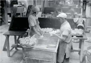  ??  ?? Workers dip pots into a vat of glaze at Wedgwood in Stoke- on-Trent, 1930