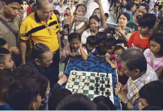  ??  ?? Zambales Gov. Amor Deloso, an avid chess player himself, and GM Eugene Torre essay the ceremonial moves surrounded by some of the bumper crop of entries in the just-concluded National Age Group Chess Championsh­ips in Iba, Zambales. Philippine Sports...