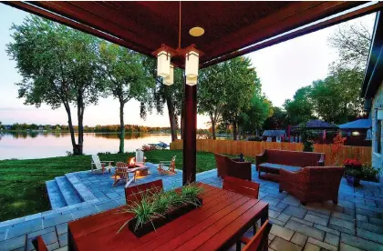  ?? PHOTO COURTESY OF PLANTENANC­E ?? A sheltered patio area with pendant lighting offers an outdoor space that can be enjoyed even at night, and the extended area with firepit and Adirondack chairs offers a perfect place to take advantage of the lakeside views.