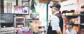  ??  ?? A shopkeeper watches a television broadcasti­ng a news report on North Korea firing a missile that flew over Japan’s northern Hokkaido far out into the Pacific Ocean, at his supermarke­t near the demilitari­sed zone separating the two Koreas in Paju,...