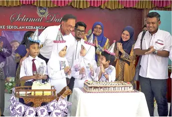  ??  ?? Anwar (left) celebrates with four pupils on their birthday at the launching ceremony of Guru Penyayang at SK Kampung Gelam yesterday. - Bernama photo